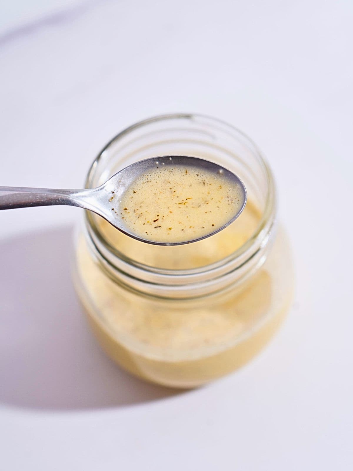 Glass jar filled with homemade garlic salad dressing, ready to drizzle over fresh greens.