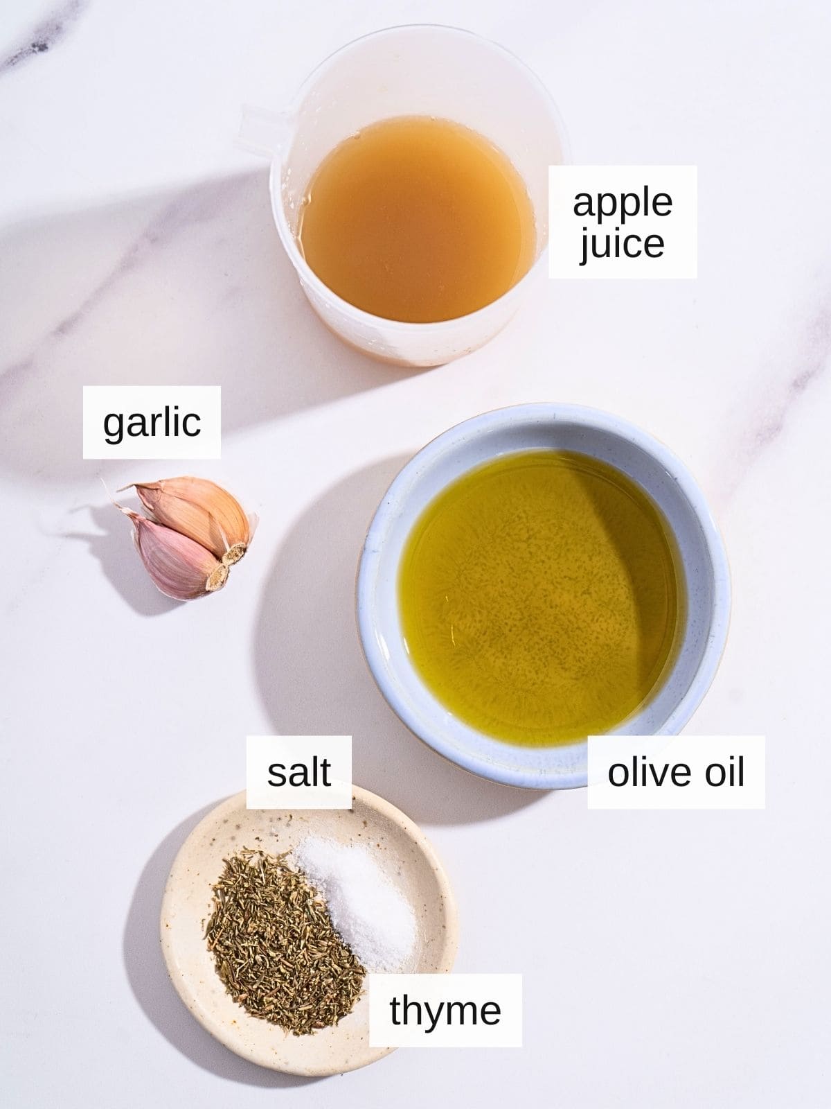 Ingredients for garlic salad dressing, including apple juice, garlic, olive oil, salt, and thyme.