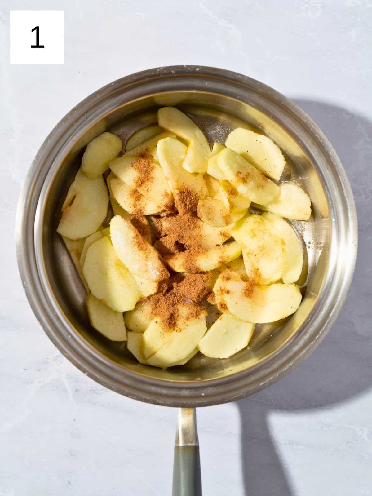 Sliced apples with sugar and ground cinnamon in a saucepan.