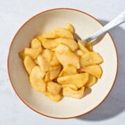 A bowl of warm stewed apples seasoned with cinnamon, showcasing tender, cooked apple slices in a comforting dessert or snack.