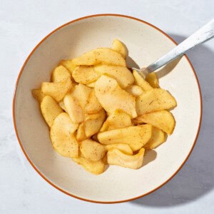 A bowl of warm stewed apples seasoned with cinnamon, showcasing tender, cooked apple slices in a comforting dessert or snack.