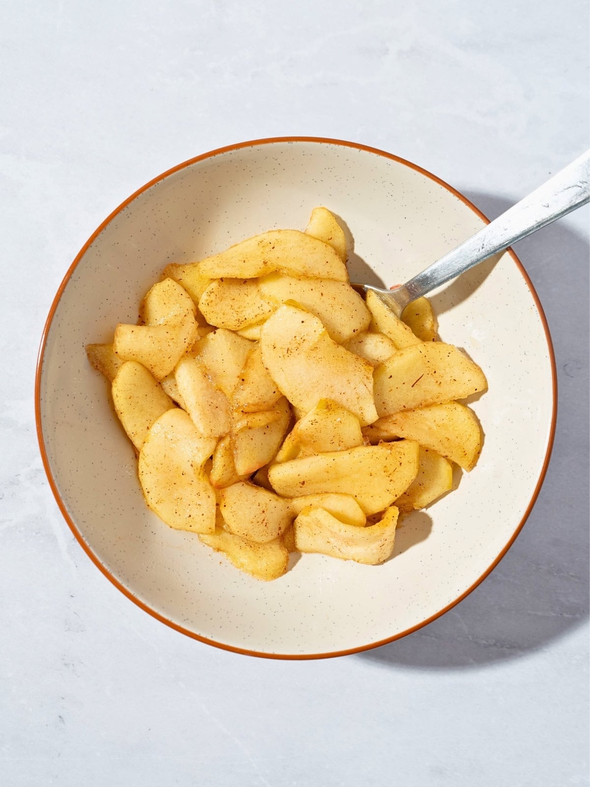 A bowl of warm stewed apples seasoned with cinnamon, showcasing tender, cooked apple slices in a comforting dessert or snack.