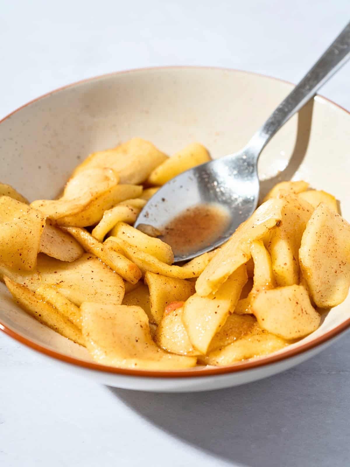 Warm stewed apples served in a bowl, with soft apple slices and a sprinkle of cinnamon.