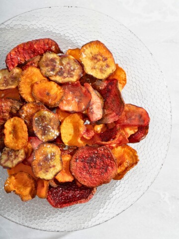 A serving of crispy homemade root vegetable chips made from sweet potatoes, beets, and carrots on a plate.