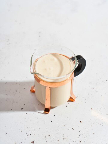 Creamy ginger garlic sauce in a clear glass container showcasing its smooth texture and rich color.