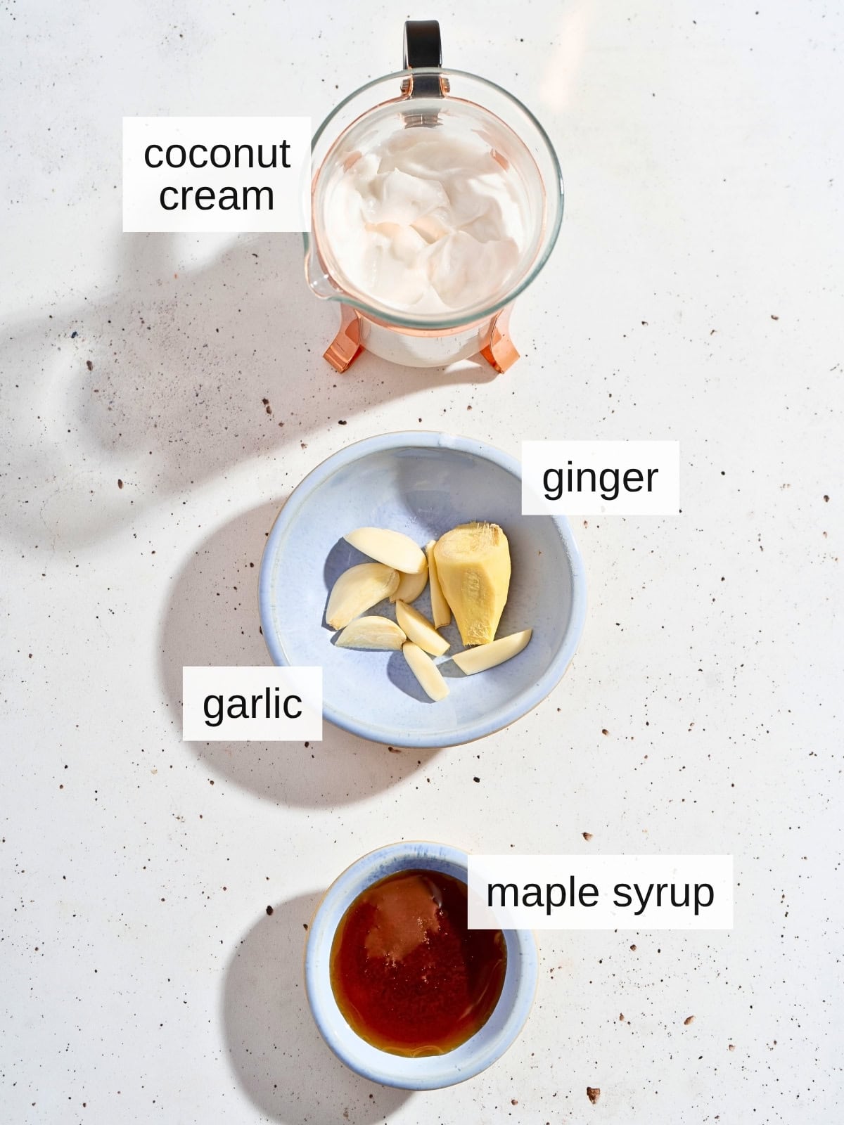 Ingredients for ginger garlic sauce, including coconut cream, fresh ginger, garlic, and maple syrup.