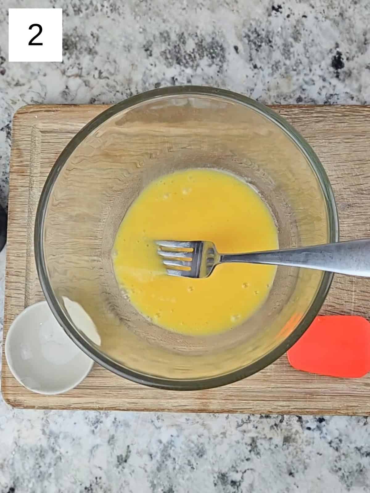 A mixture of egg and oil in a glass mixing bowl.
