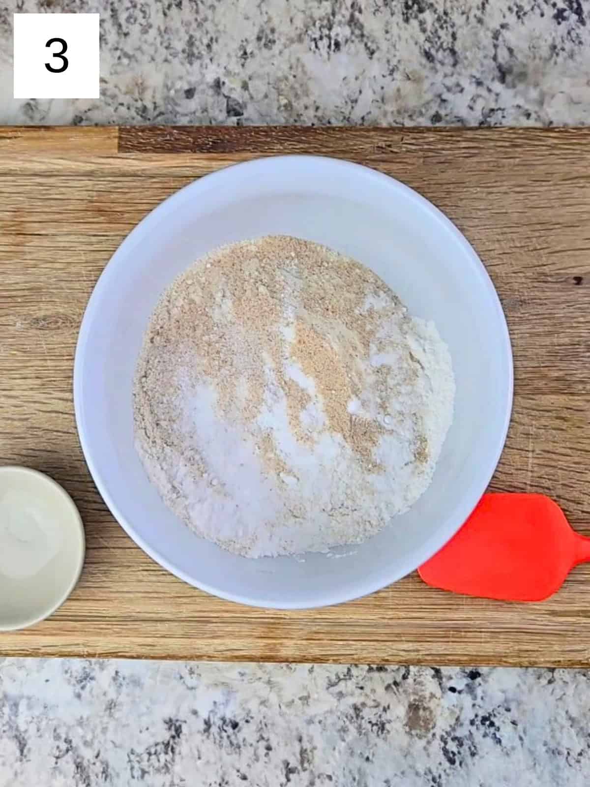 A bowl filled with flour, psyllium husk powder, baking powder, salt, and monk fruit powder.