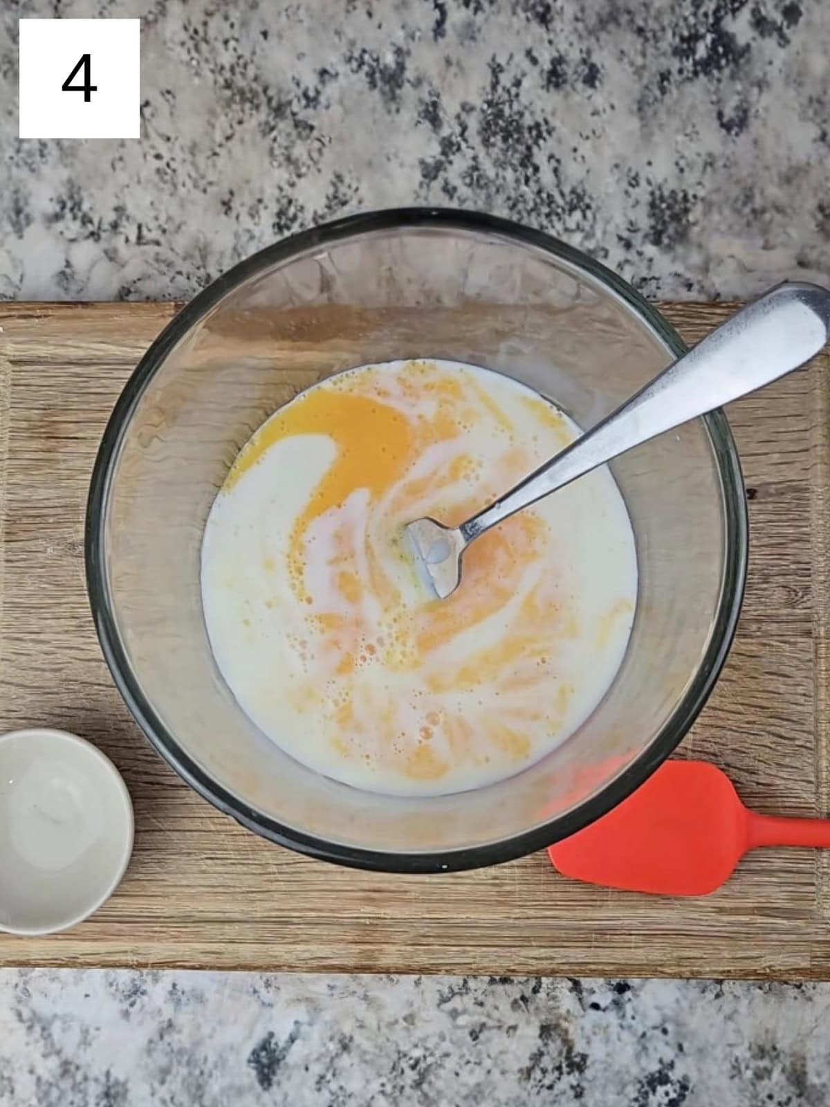A glass bowl filled with egg mixture and milk.