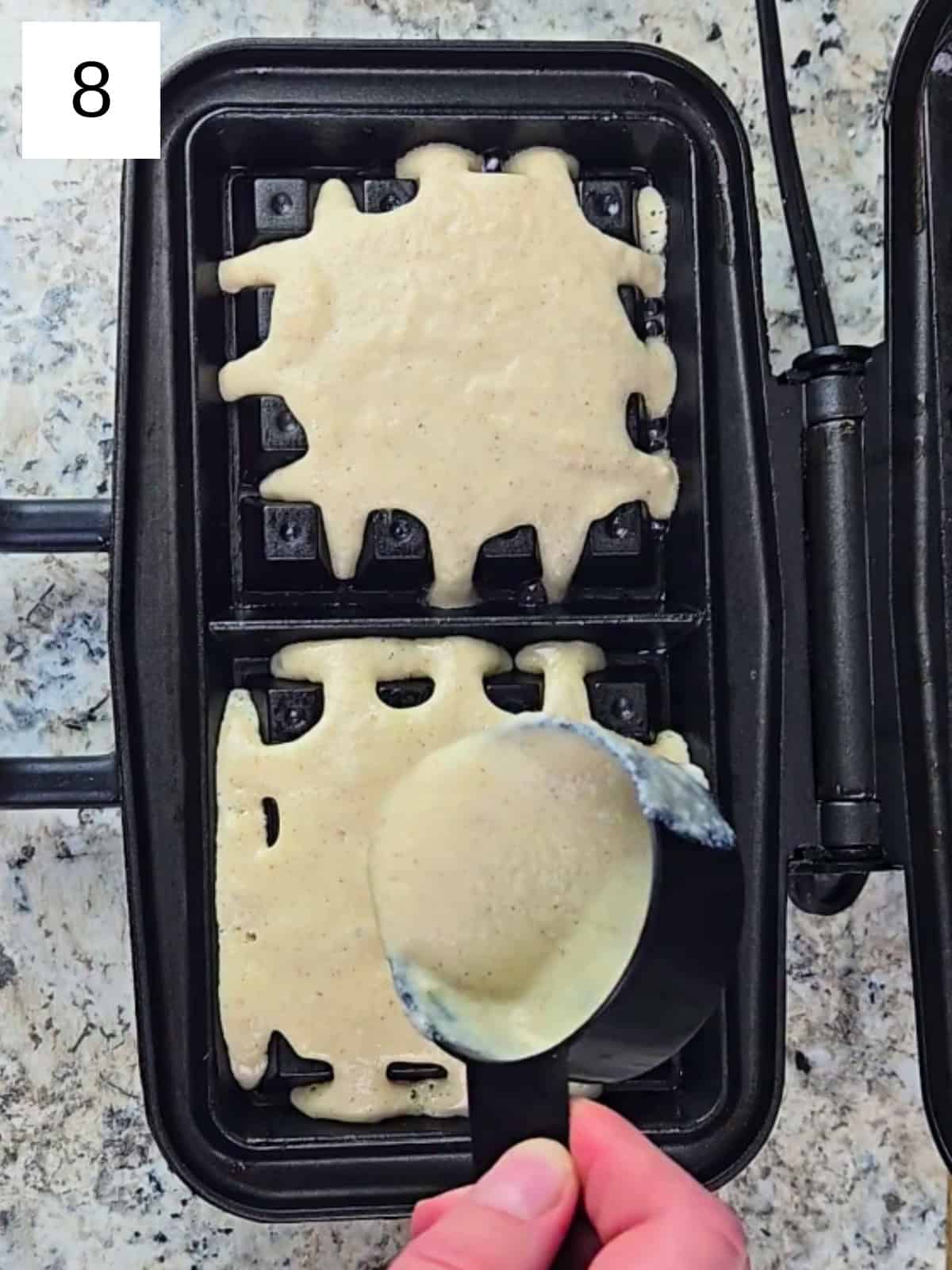 A preheated waffle maker filled with freshly poured waffle batter, ready to cook.