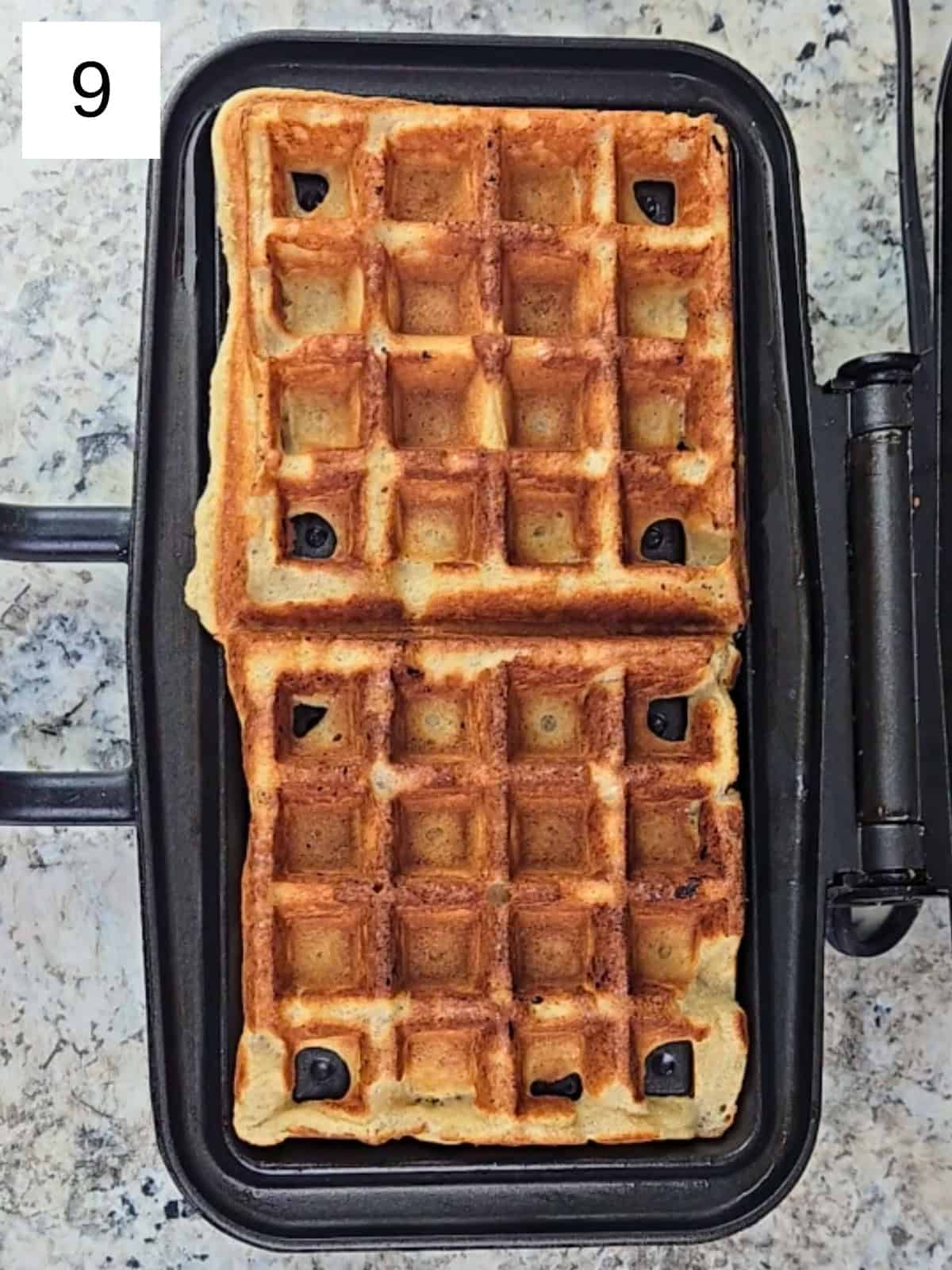 A preheated waffle maker holding freshly cooked golden waffles, just finished and ready to serve.