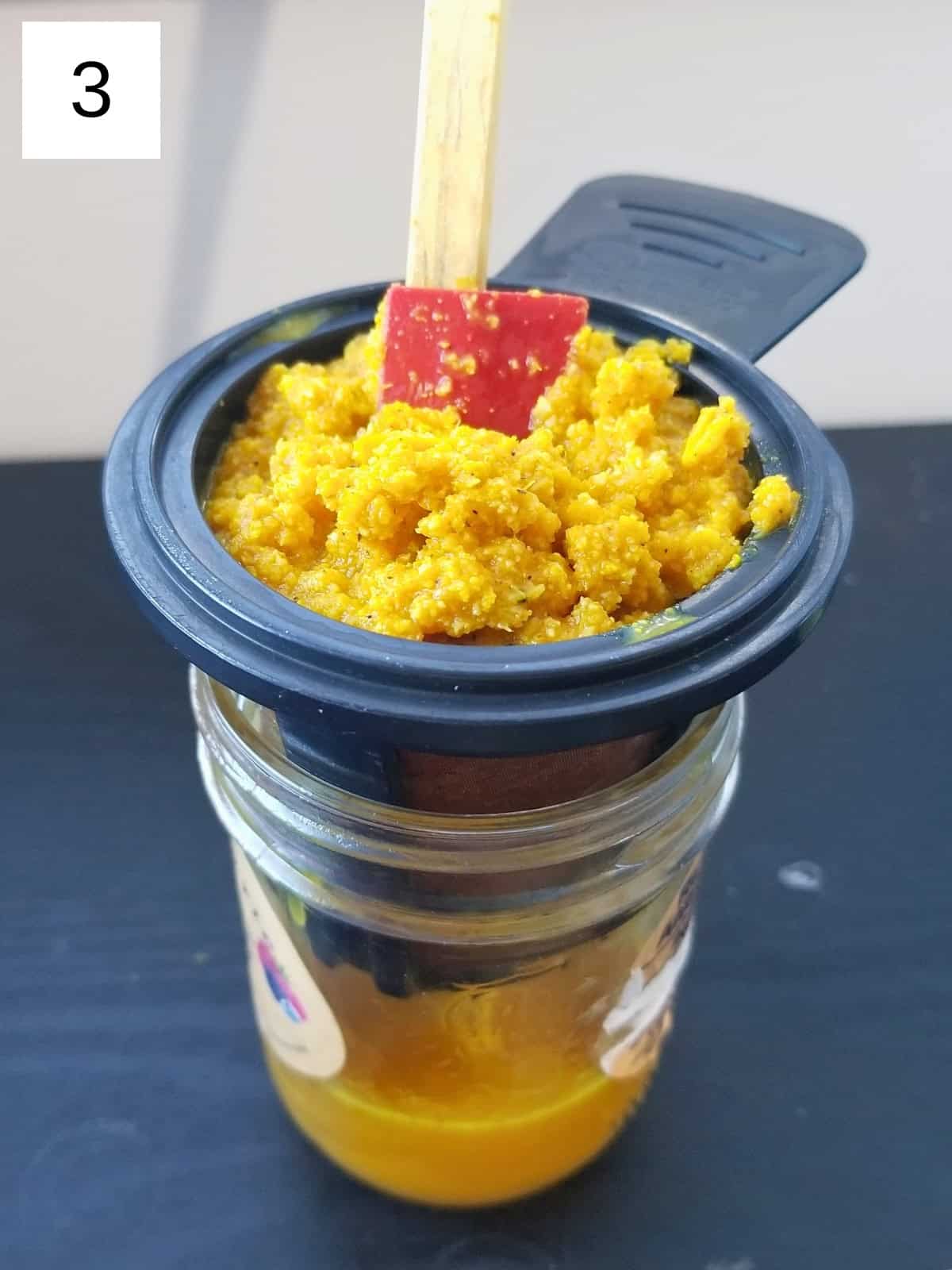 Step 3 for making Ginger Turmeric Shots: filtering the mixture to create a smooth ginger shot.