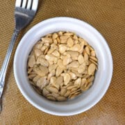 A small bowl filled with golden-brown, crispy roasted squash seeds, perfect as a healthy low-histamine snack or salad topper.