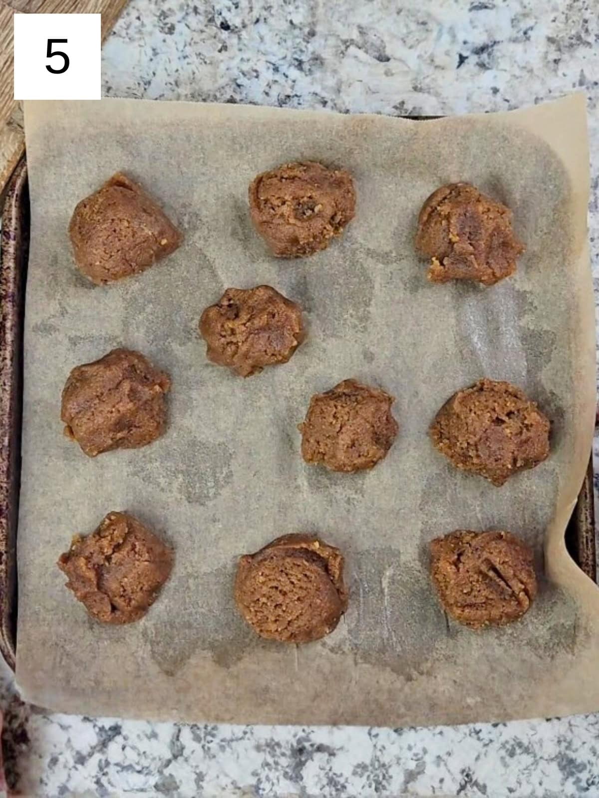 Cookie dough balls on a baking tray with parchment paper.