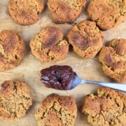 Freshly baked vanilla almond cookies on a wooden chopping board with a spoonful of sauce alongside.