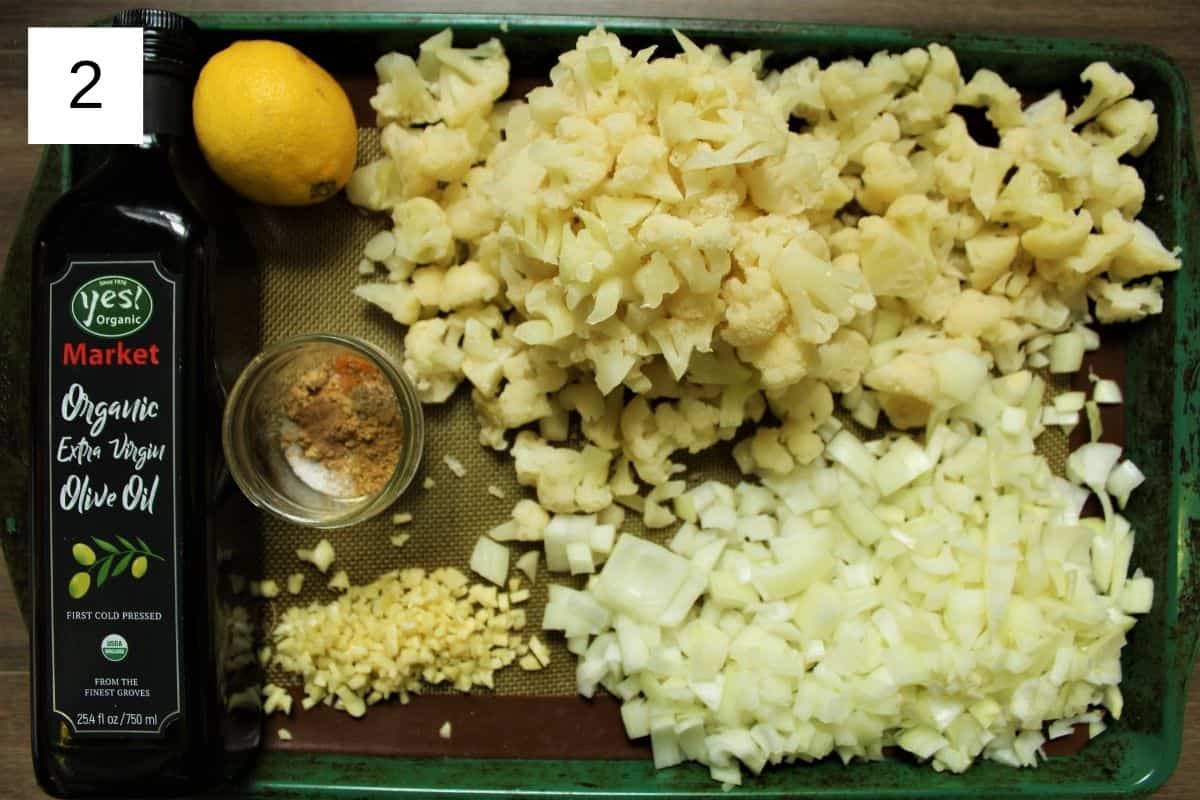 ingredients for baked cauliflower, including camu camu powder, sea salt, fresh cauliflower, olive oil, coriander seed, turmeric, lemon, garlic, cardamom, cumin, ginger, and sweet onion.