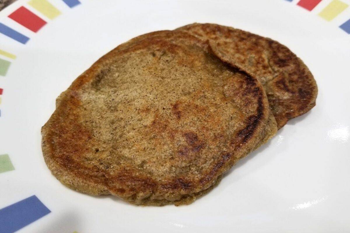 Cooked pancakes stacked on a plate, golden brown and fluffy, ready to serve.