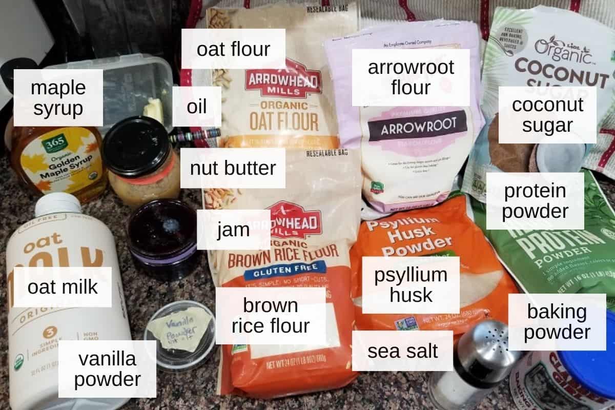 Ingredients for oat milk pancakes, including oat milk, oat flour, vanilla powder, brown rice flour, psyllium husk powder, arrowroot flour, coconut sugar, hemp protein powder, salt, baking powder, frying oil, and some sauce or topping options, including maple syrup, nut butter, and blueberry jam.