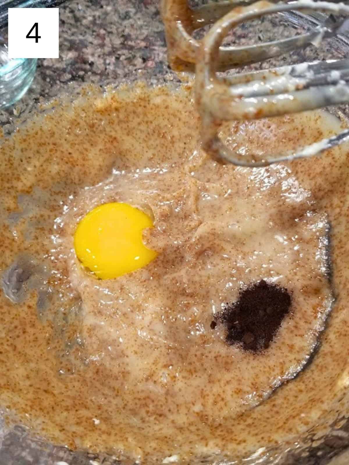 Creamed mixture of butter, coconut sugar, and honey in a glass mixing bowl, with egg yolk and vanilla powder.
