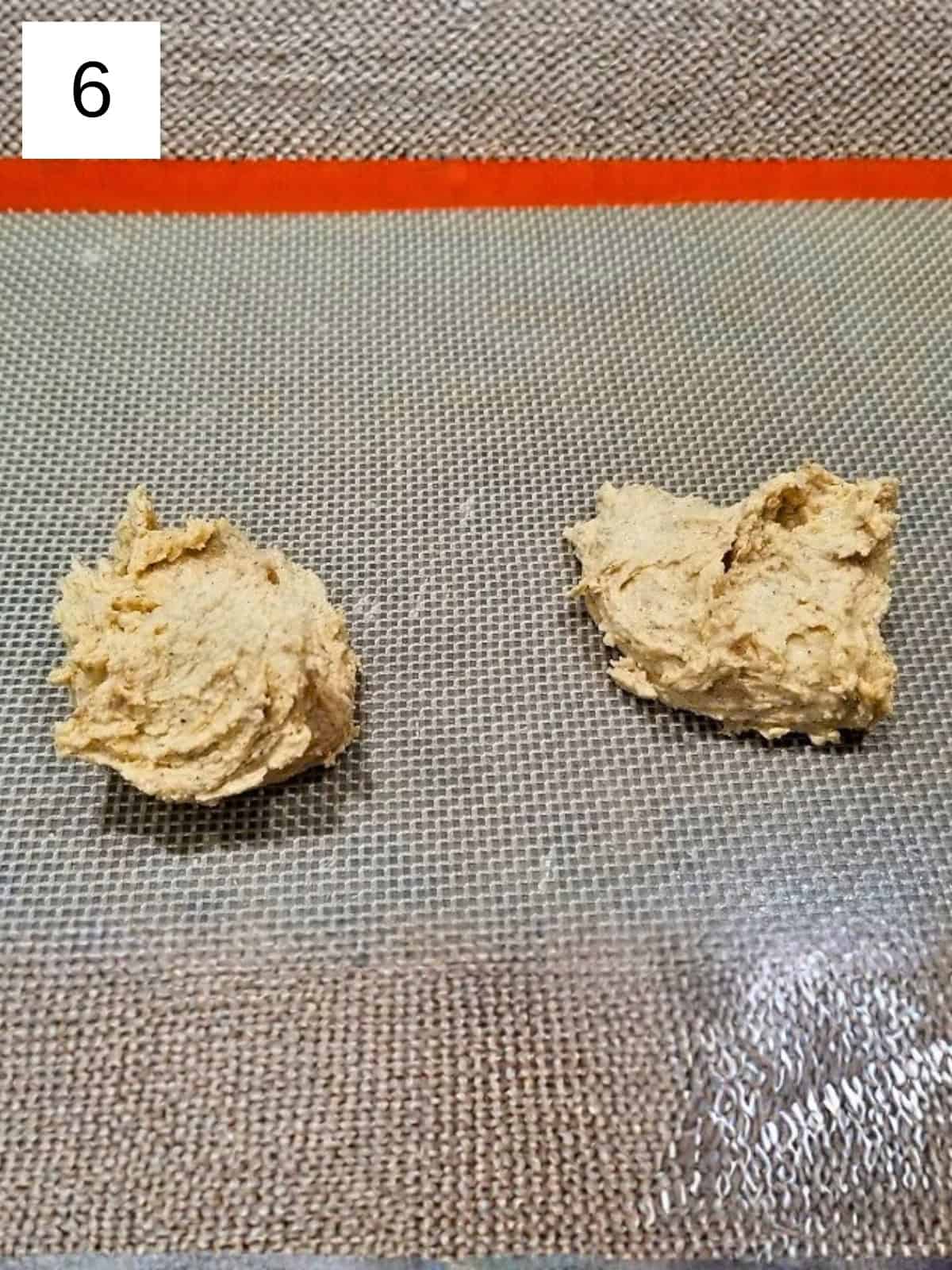 Scooped portions of cookie dough arranged on parchment paper, ready for baking.