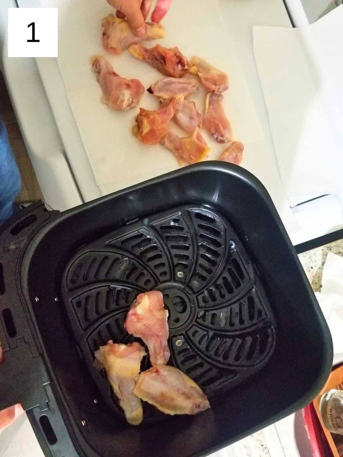 Raw chicken wings placed in an air fryer basket, prepared for defrosting.
