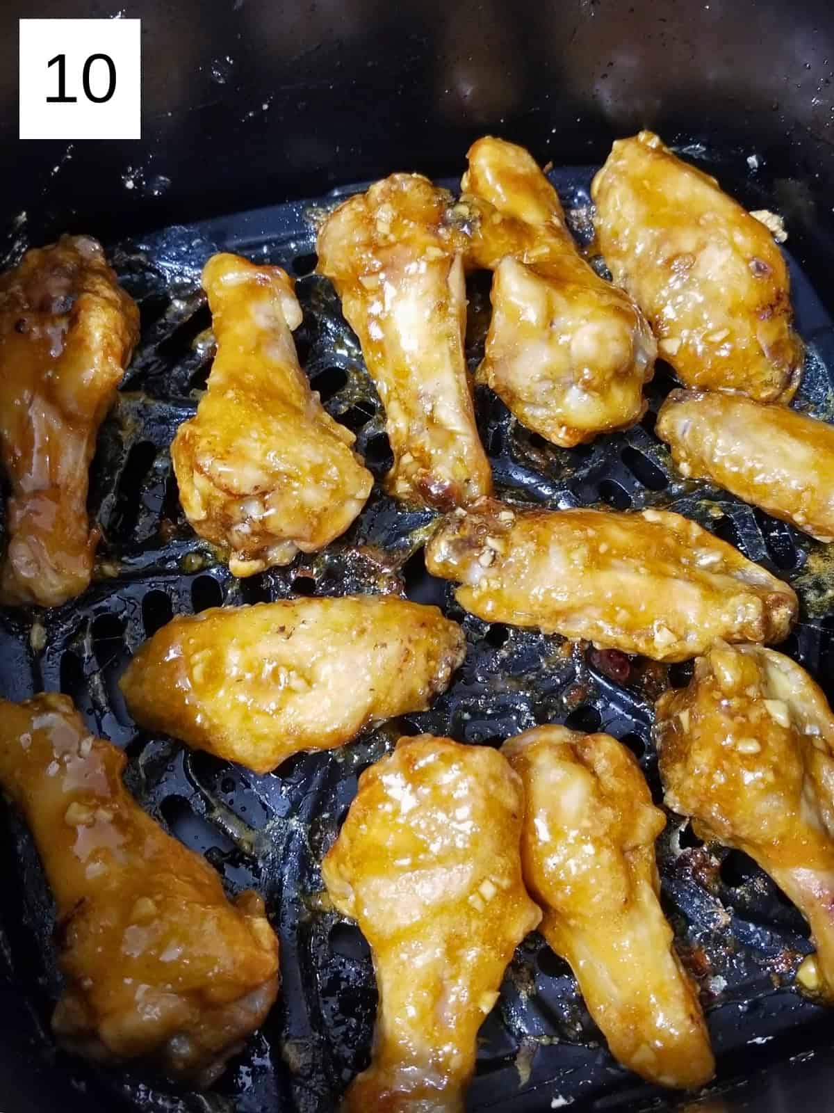 Chicken wings, coated with honey garlic sauce, in an air fryer.
