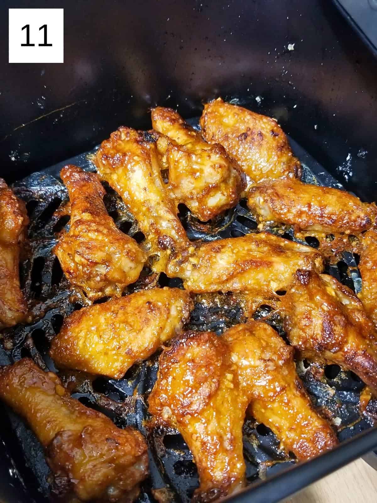 Air fried chicken wings, seasoned with honey garlic sauce, in an air fryer.