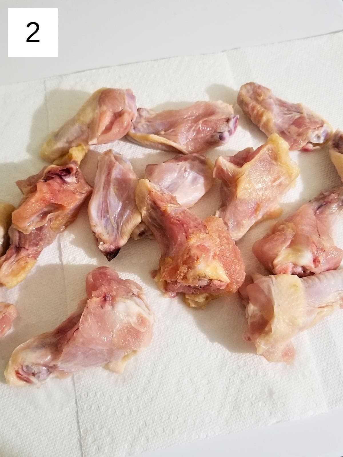 Defrosted raw chicken pieces patted dry with a paper towel.