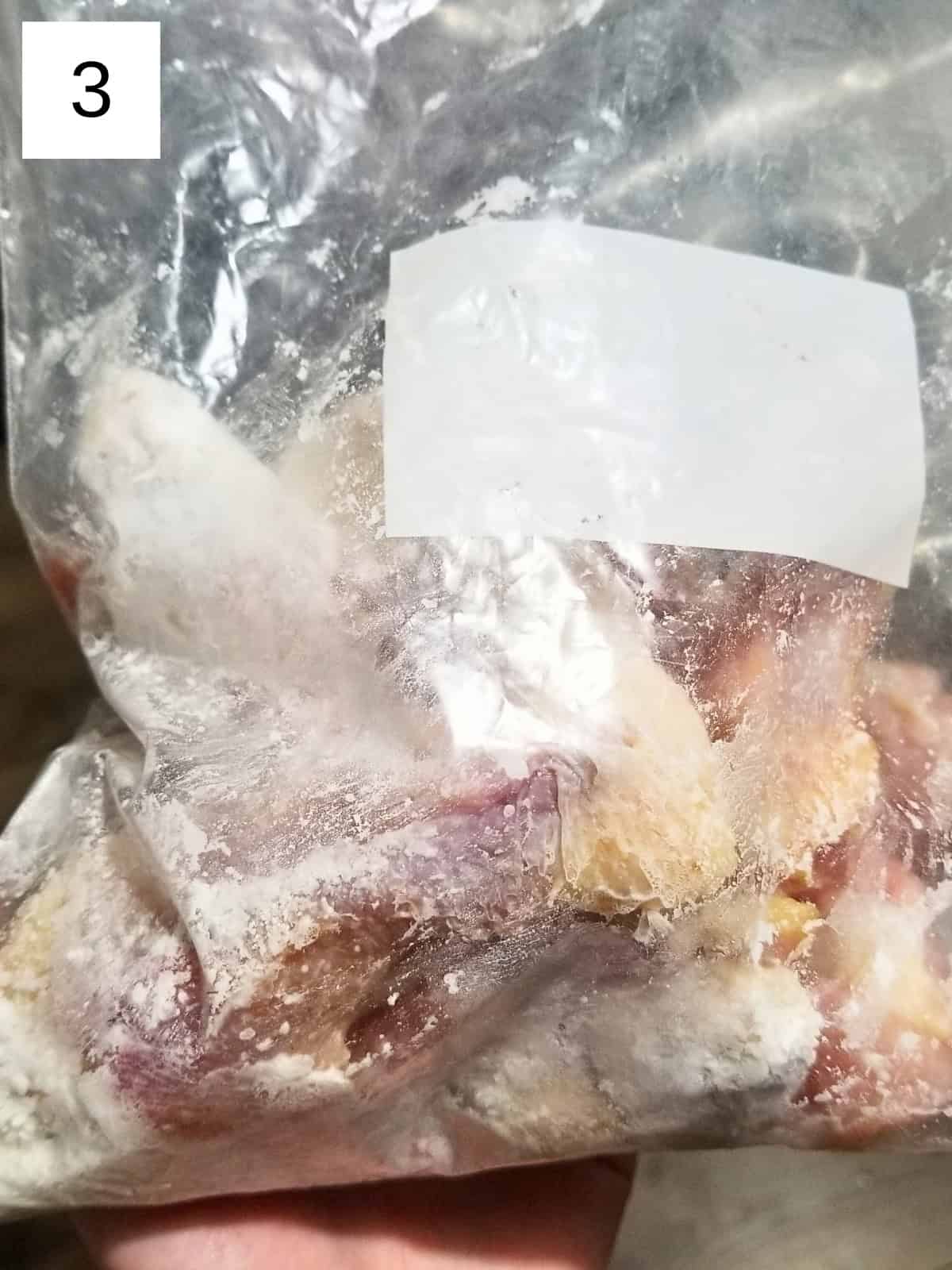 Raw chicken pieces in a zip-top freezer bag coated with salt and baking powder seasoning.