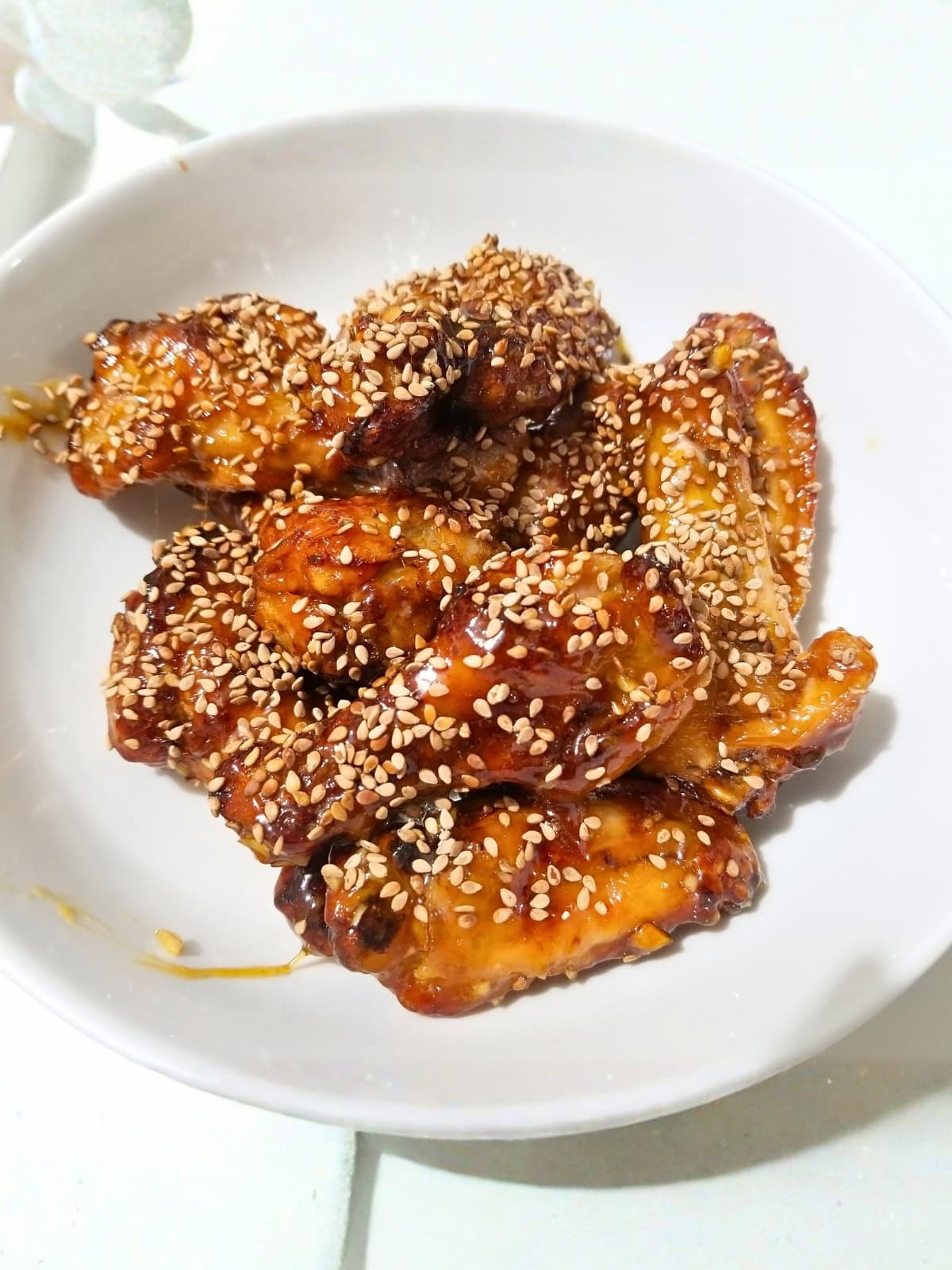 Air fried honey garlic chicken wings, coated with sesame seeds, on a plate.