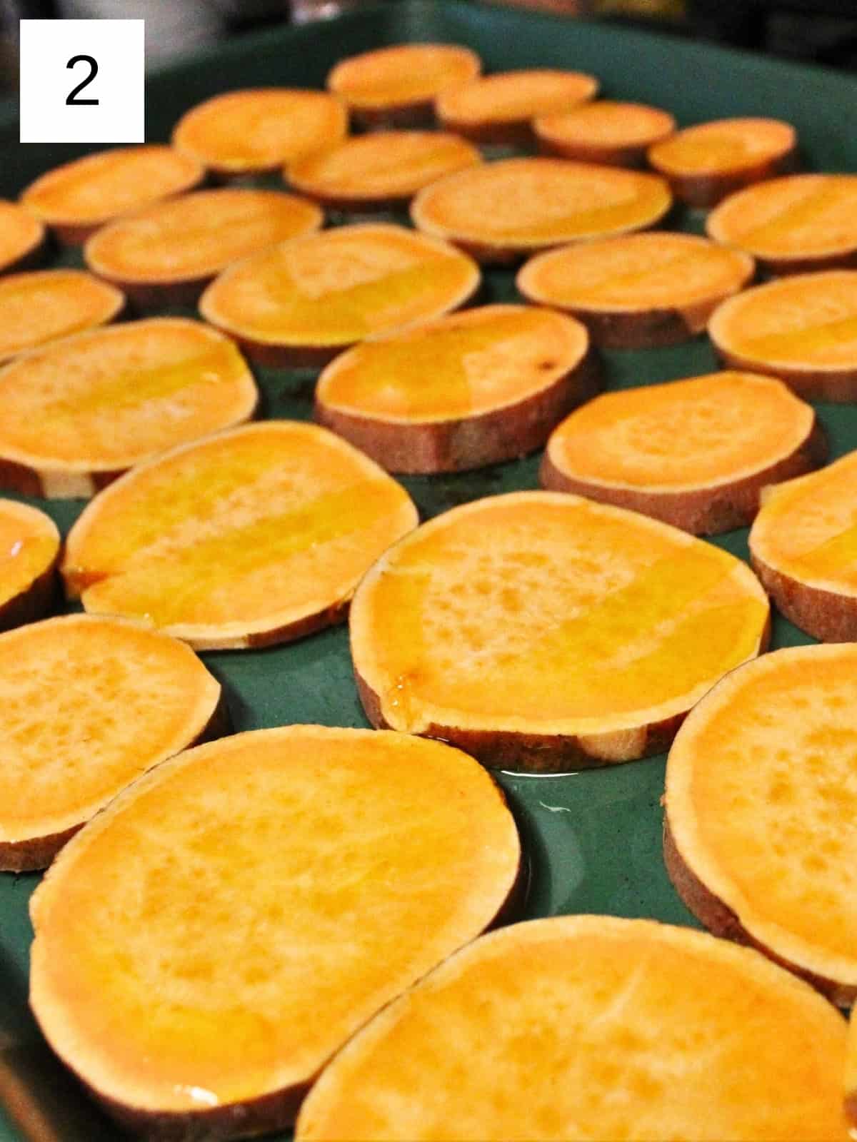 equally sliced sweet potatoes layered on a baking tray.