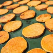 sweet potato slices layered on a baking tray.