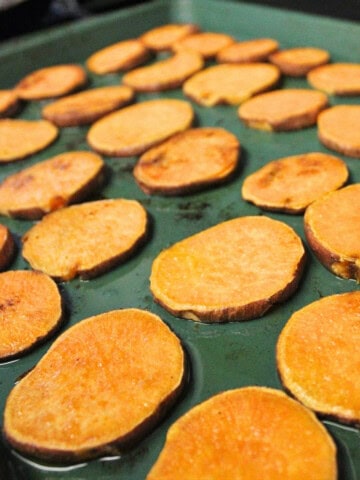 sweet potato slices layered on a baking tray.