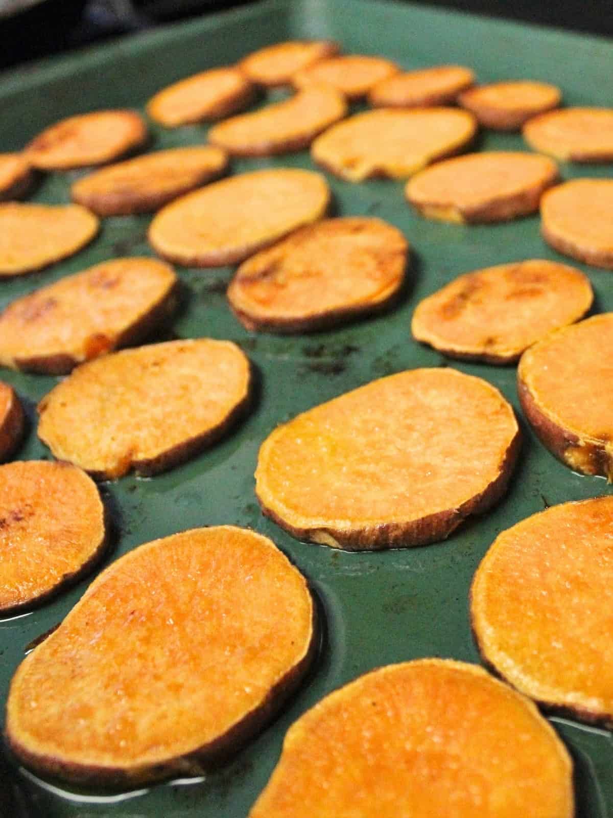 sweet potato slices layered on a baking tray.