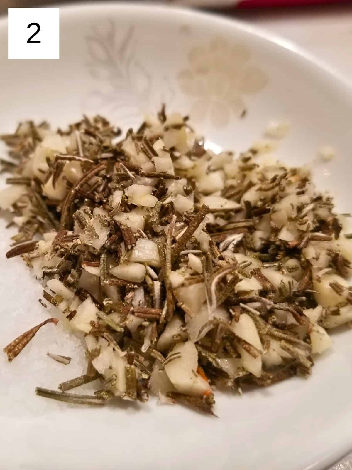 a mixture of minced garlic, dried rosemary, and spices in a saucer.