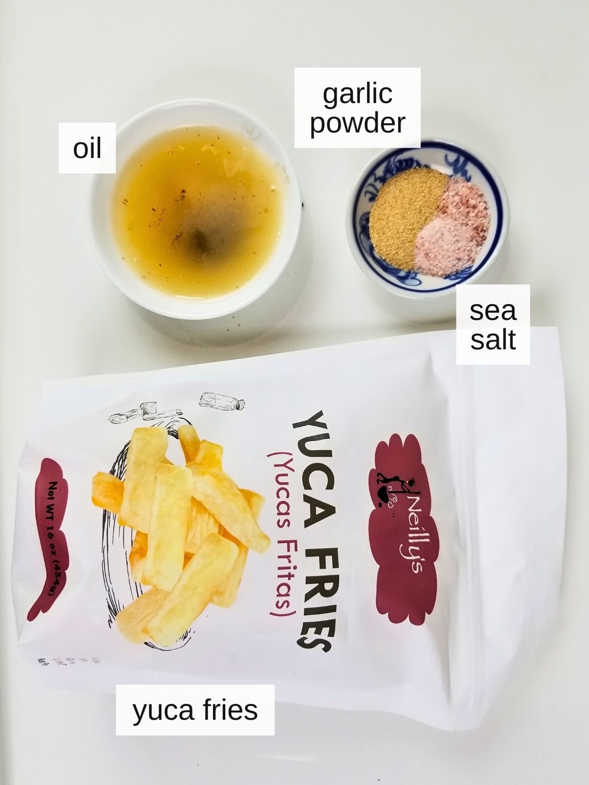 Ingredients for air fryer yuca fries, including oil, garlic powder, sea salt, and a pouch of frozen yuca fries.