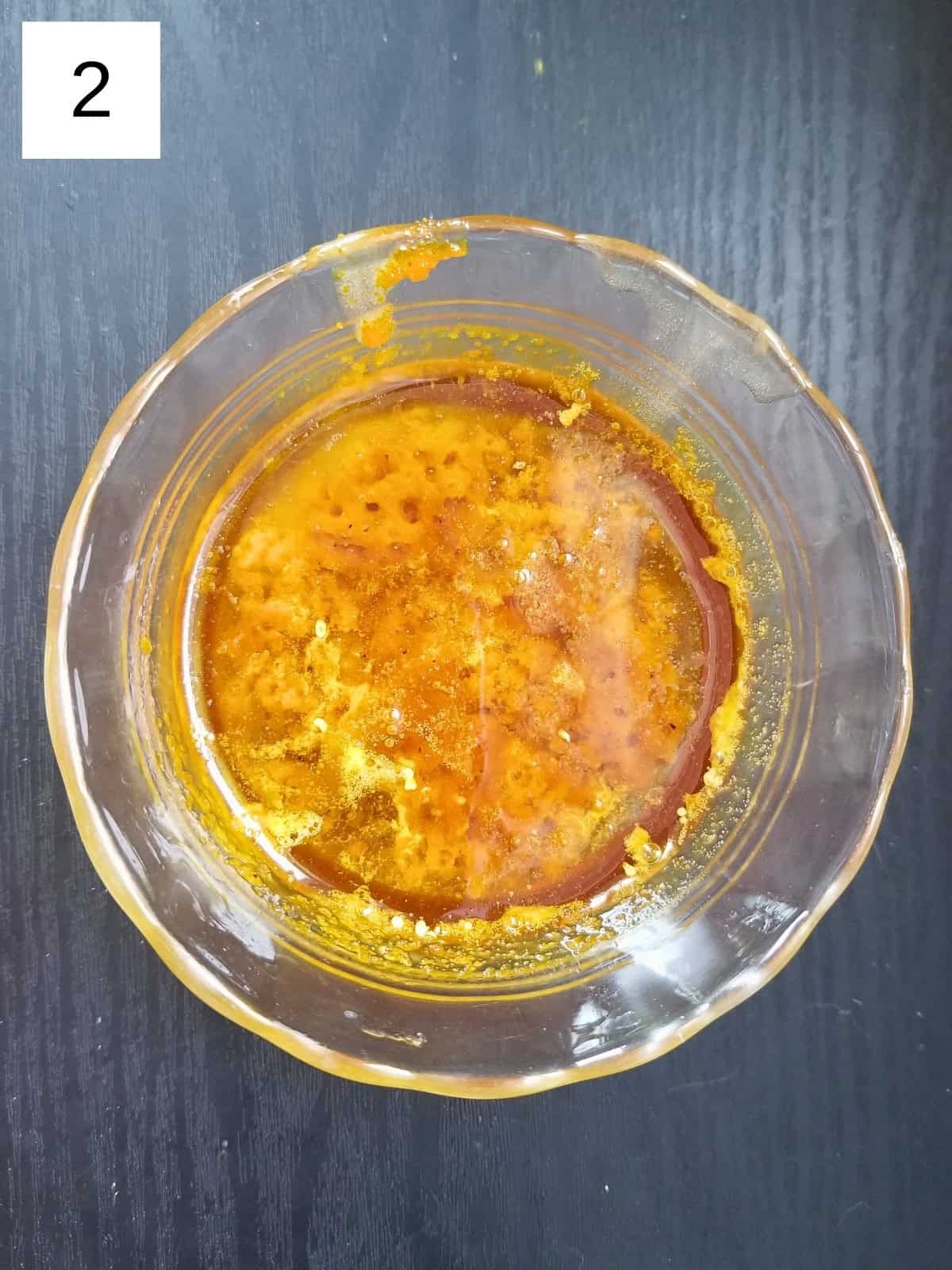 A mixture of coconut oil, honey, and turmeric paste in a glass bowl.