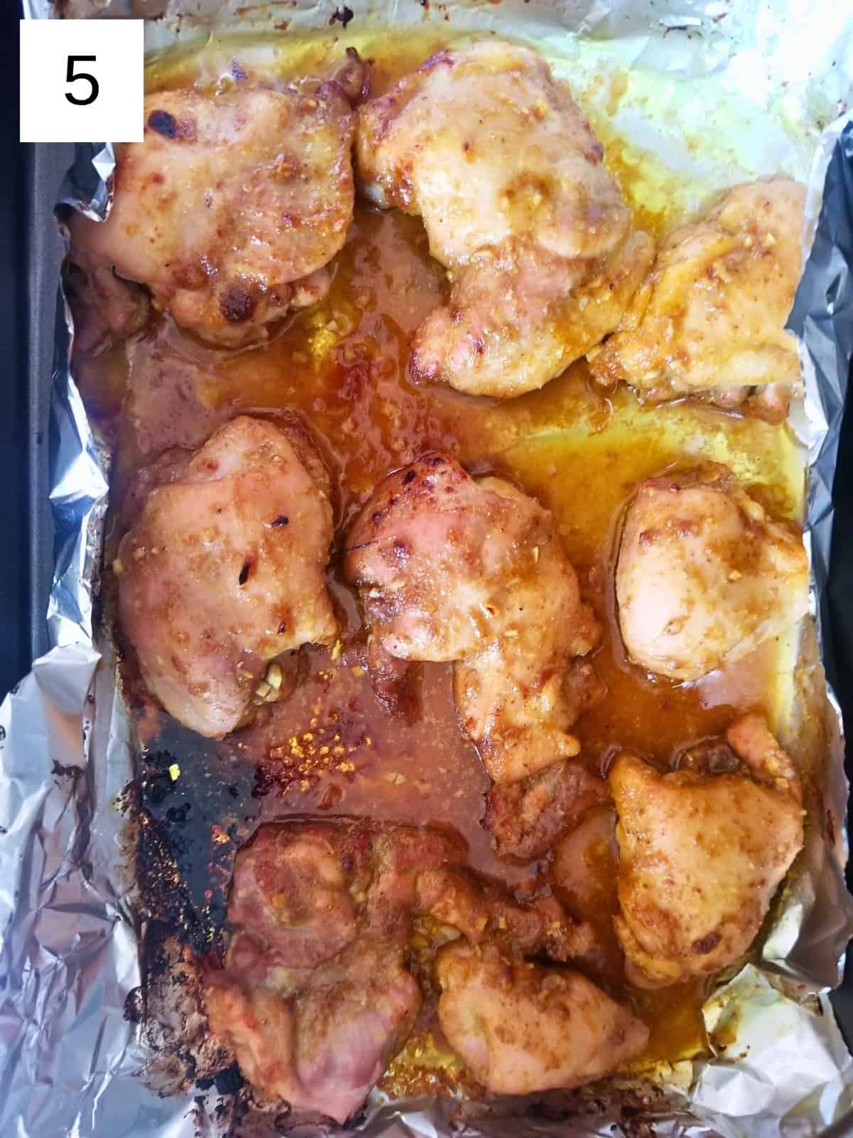 Baked honey turmeric chicken thighs on a baking tray.