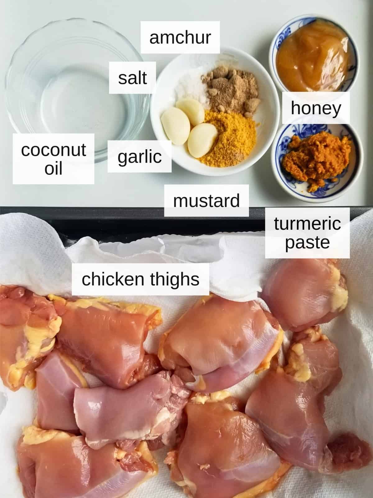 Ingredients for turmeric chicken thighs, including coconut oil, sea salt, garlic, amchur powder, mustard powder, honey, turmeric pate, and chicken thighs.