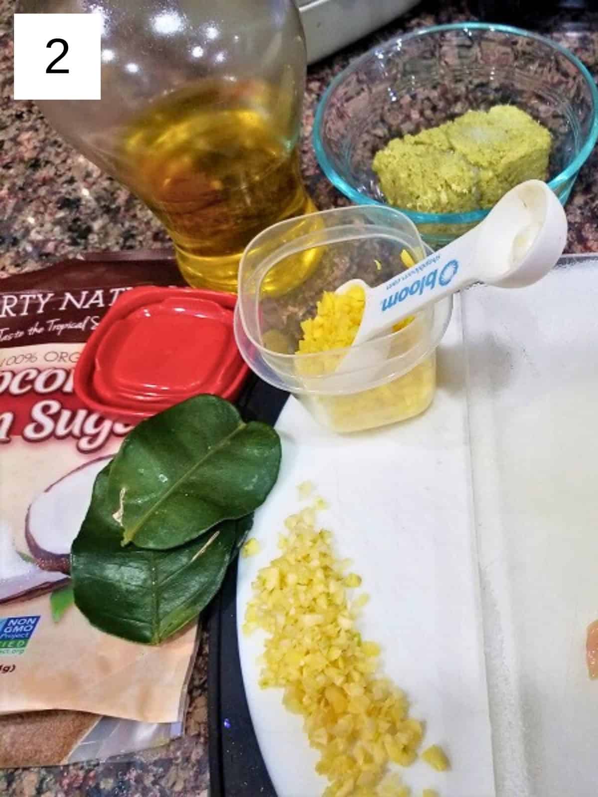 Ingredients for lemongrass chicken, including oil, frozen lemongrass, lime leaves, coconut sugar, minced garlic, and minced ginger.