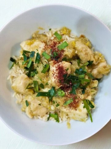 Cooked lemongrass chicken in a bowl, topped with fresh chopped herbs and additional seasonings.