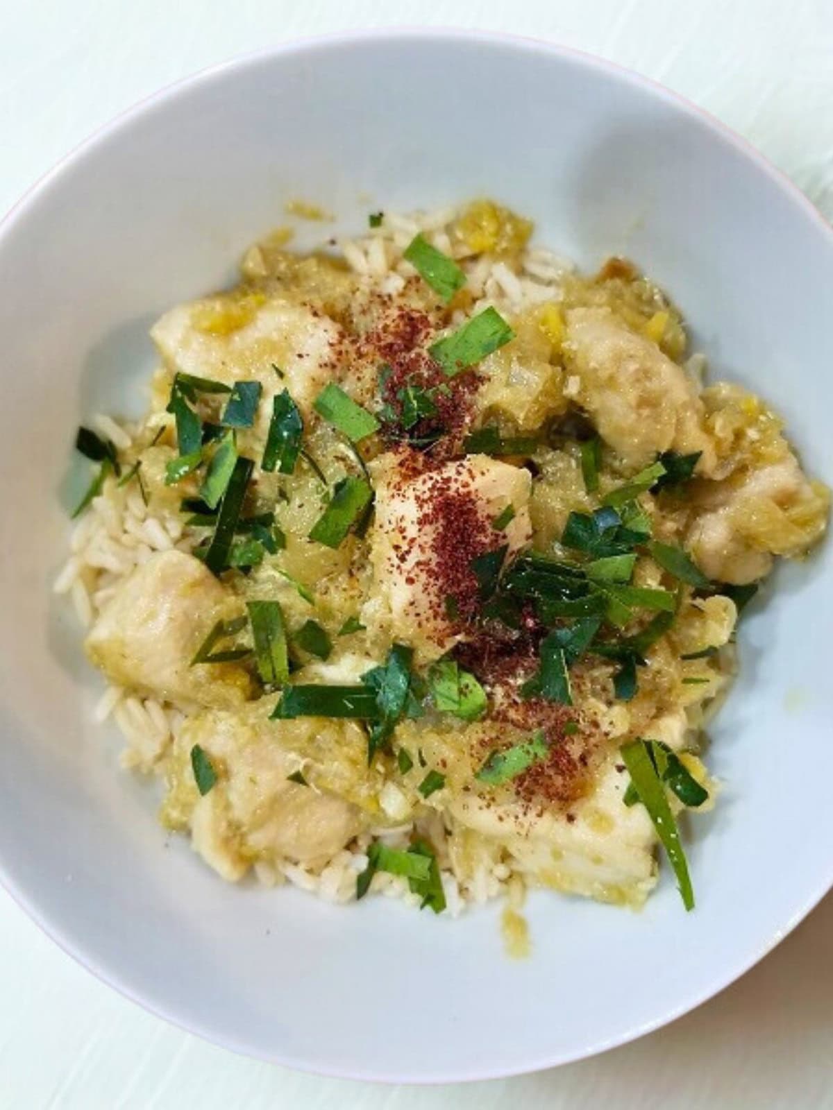Cooked lemongrass chicken in a bowl, topped with fresh chopped herbs and additional seasonings.