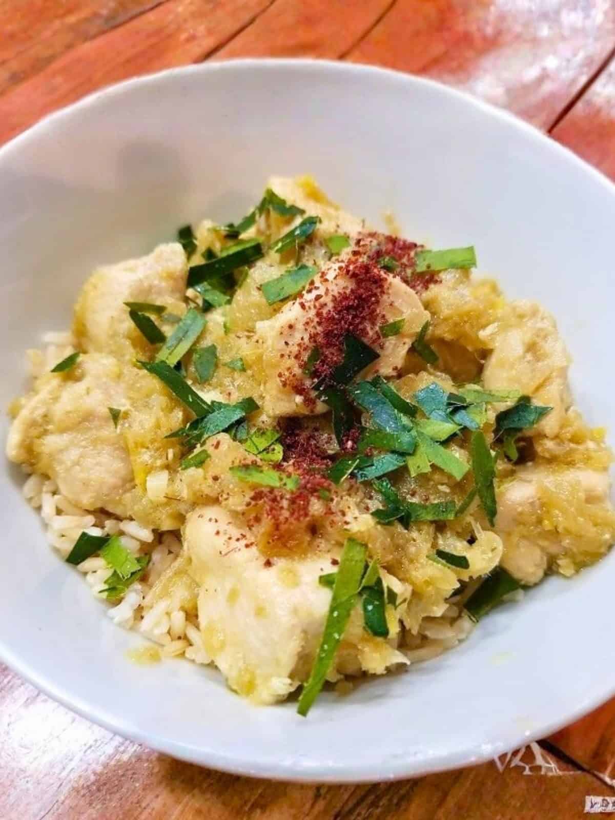 Cooked lemongrass chicken in a bowl, topped with fresh chopped herbs and additional seasonings.