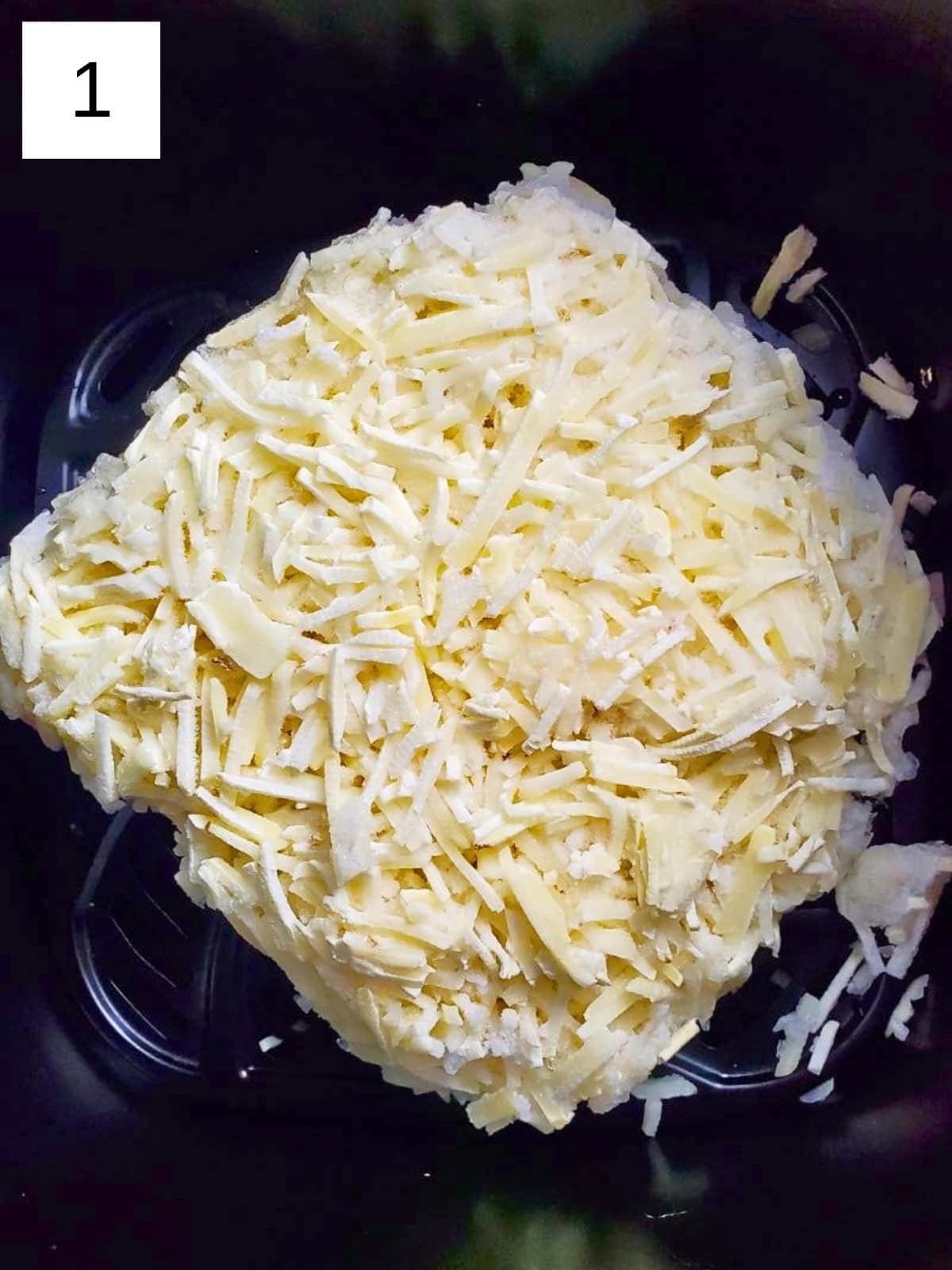 A block of frozen hashbrowns inside an air fryer.