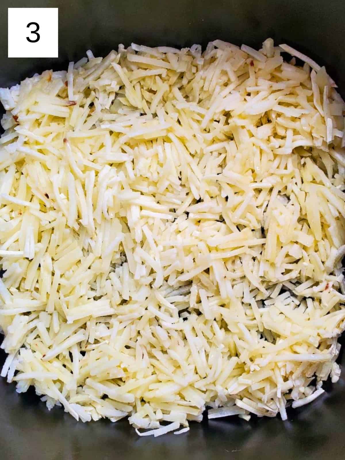 Uncooked shredded hashbrowns inside an air fryer.