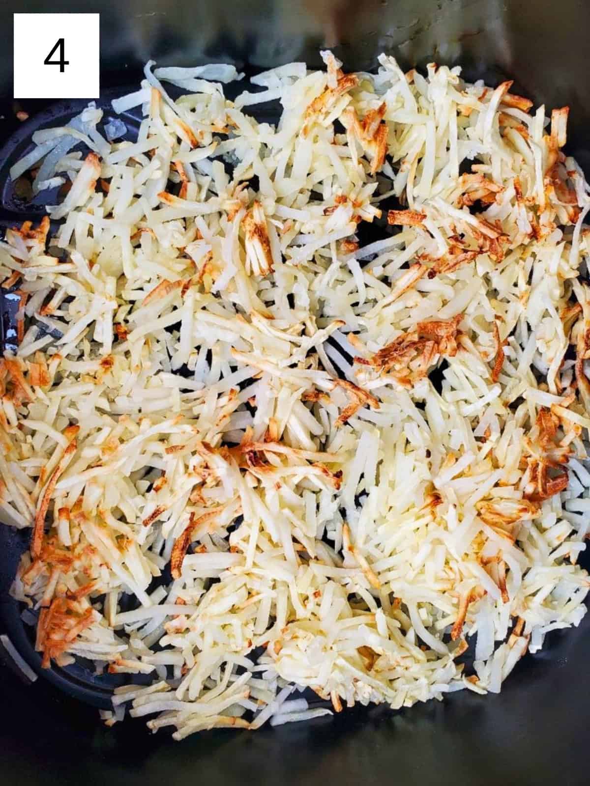 Browned shredded hashbrowns inside an air fryer.