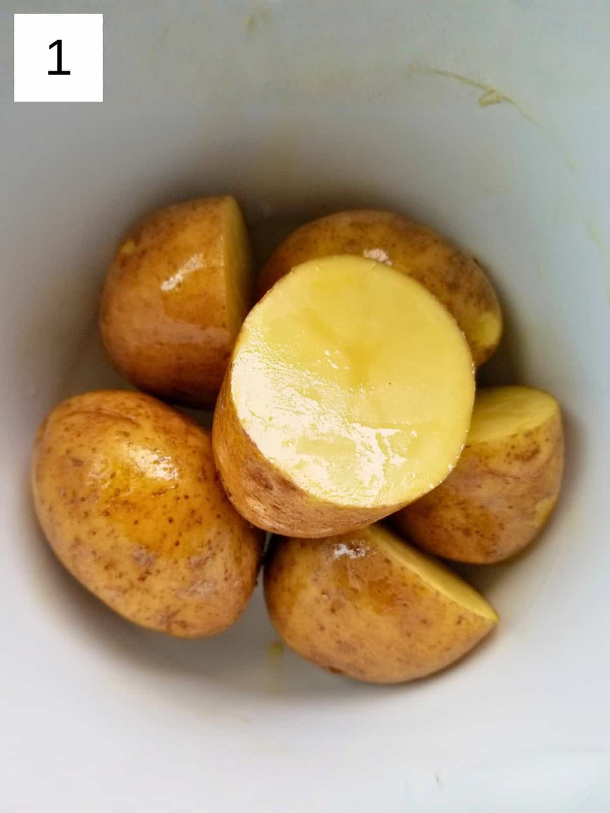 Potatoes coated with oil in a bowl.