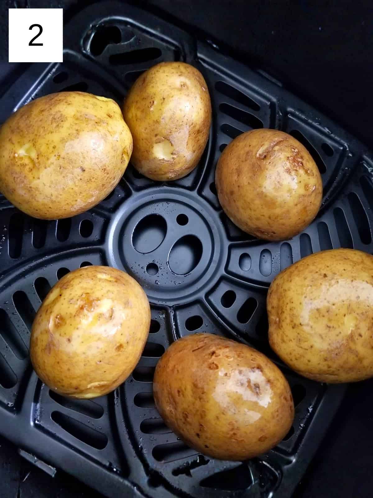 Raw potatoes in an air fryer basket.