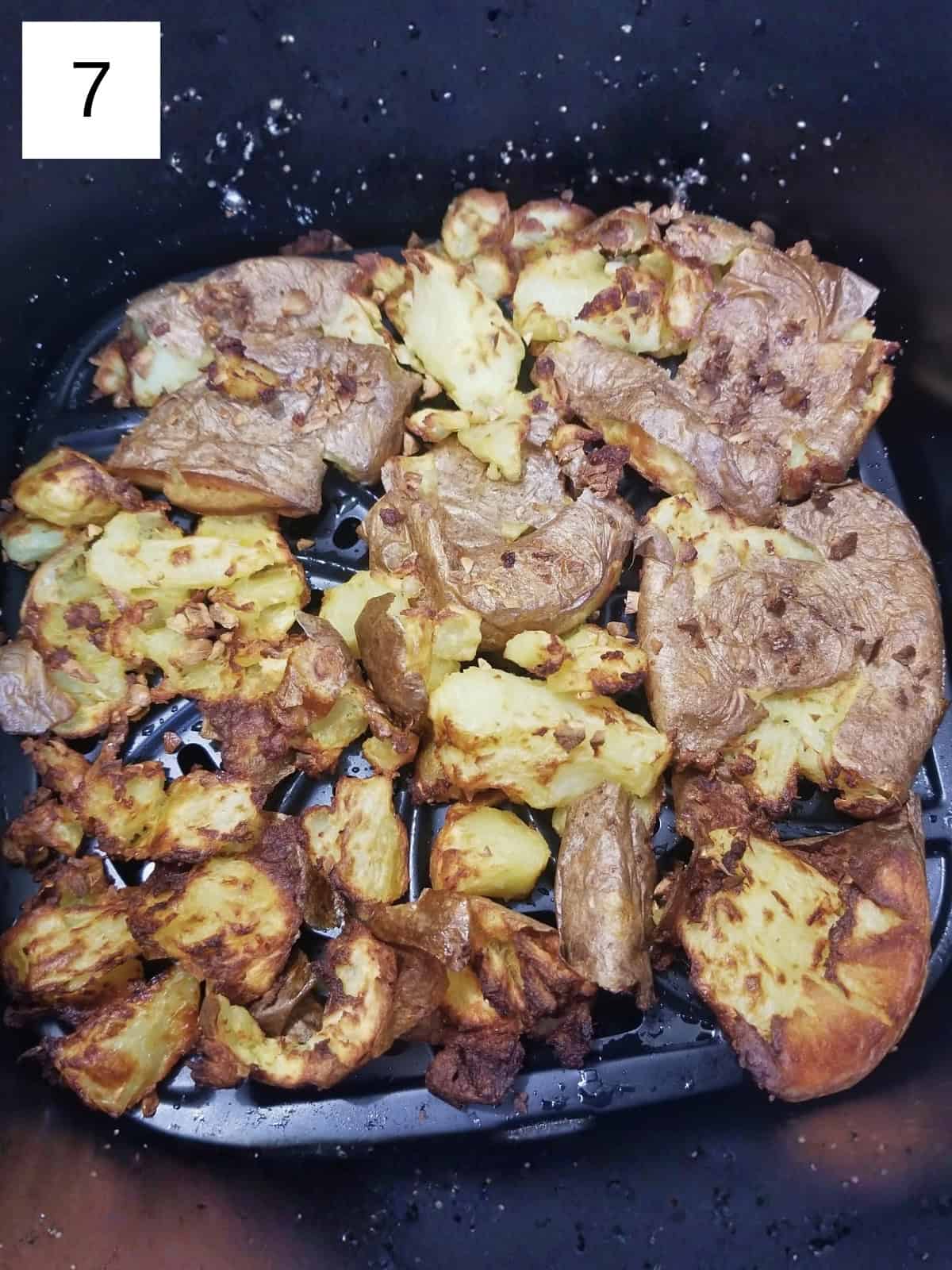 Air fried garlic smashed potatoes in an air fryer basket.