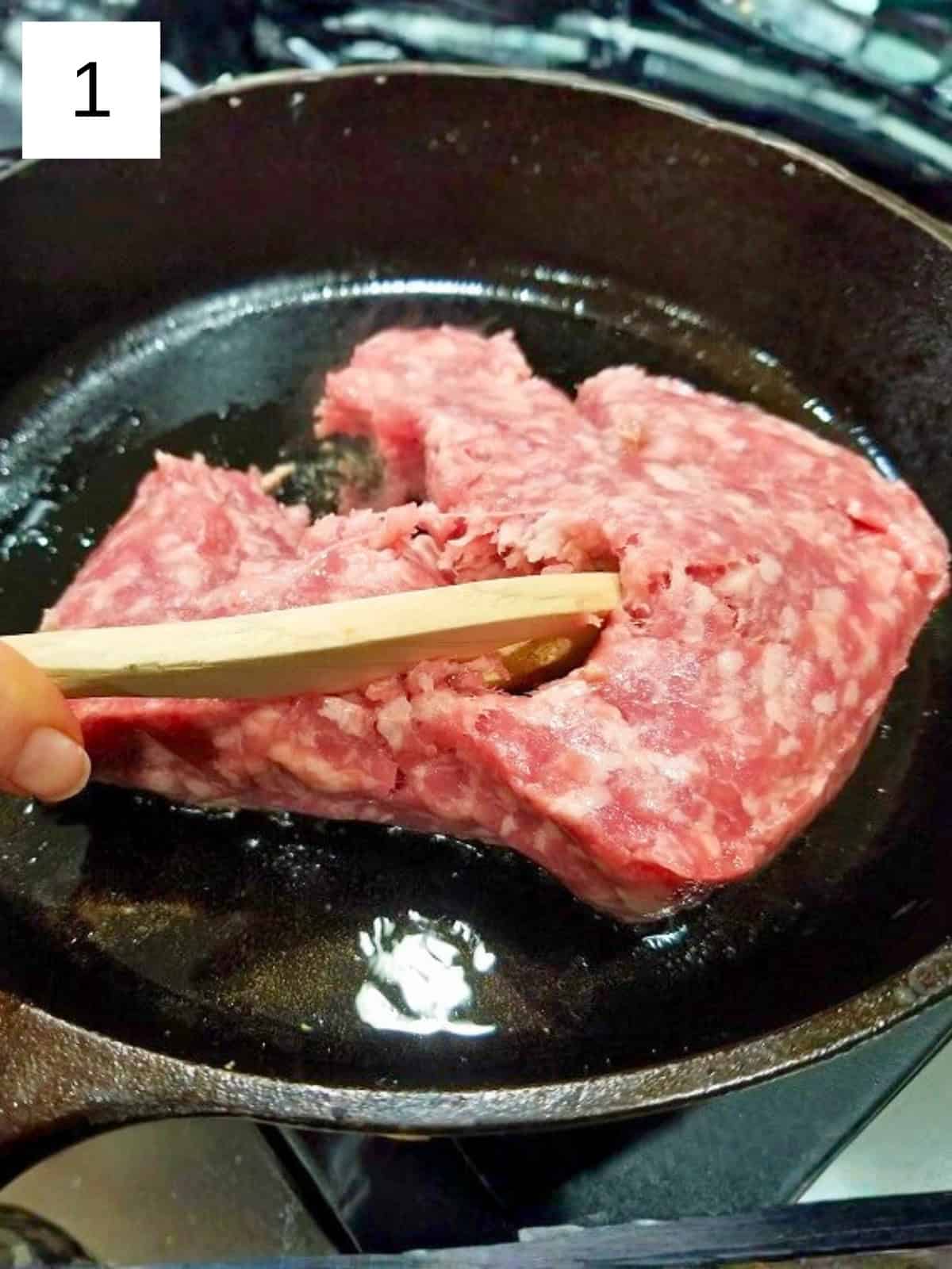 Raw ground chicken in a cast iron pan.